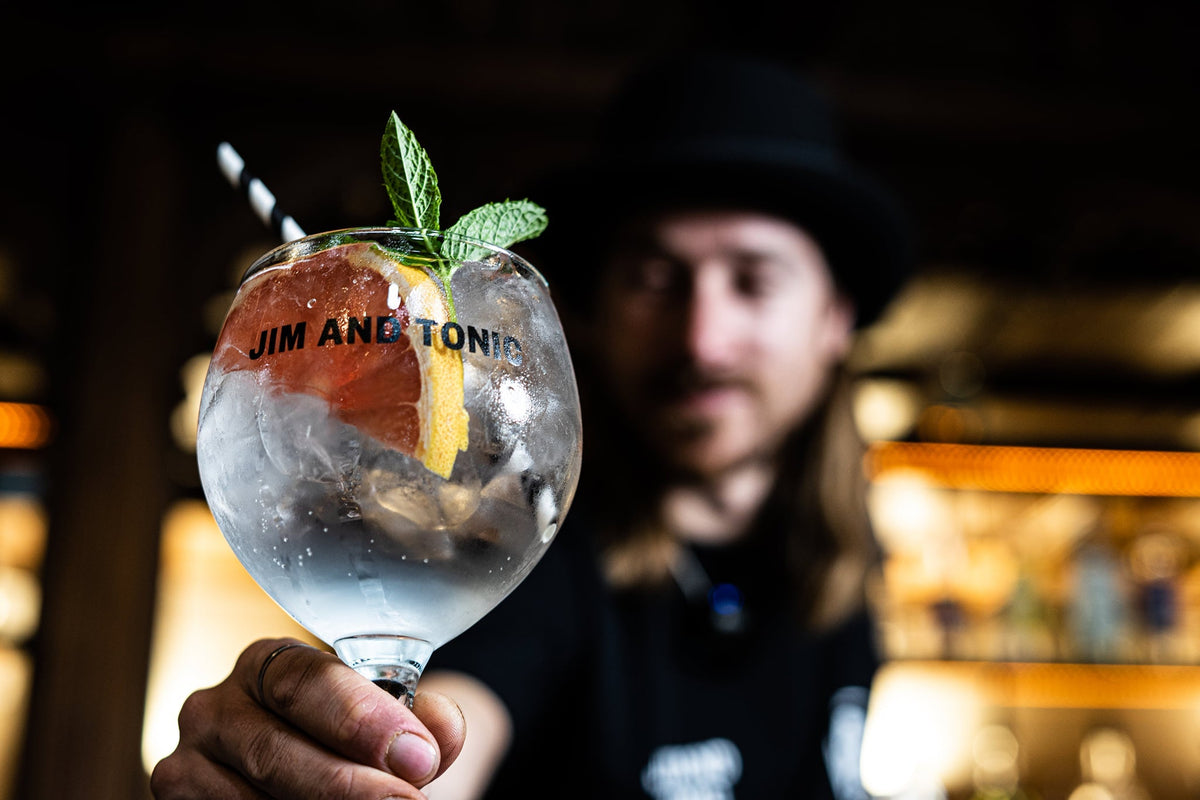 Mixologist making perfect gin and tonic with copa balloon glass, ice and grapefruit.