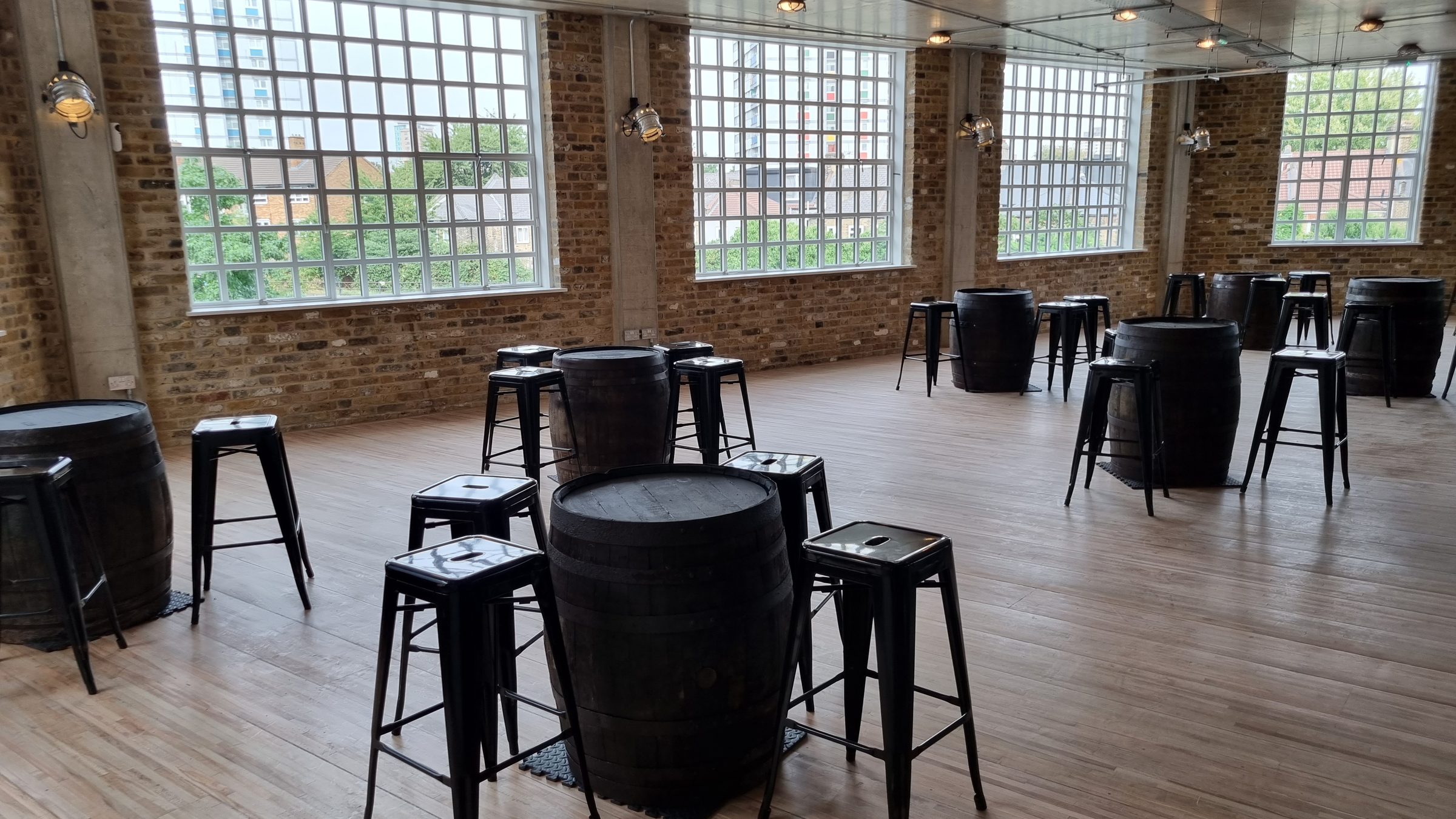 A room with stools around barrels that are being as in place of tables.