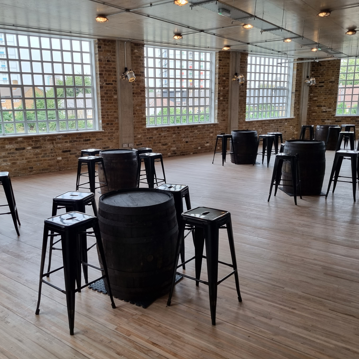 A room with stools around barrels that are being as in place of tables.